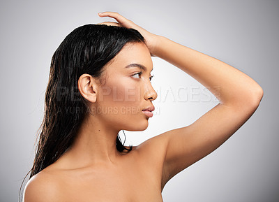 Buy stock photo Cropped shot of an attractive young woman looking thoughtful while posing in studio against a grey background