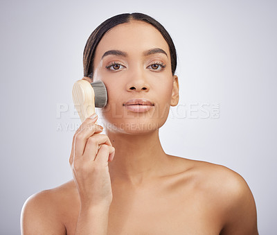 Buy stock photo Studio shot of an attractive young woman exfoliating her face with a brush against a grey background