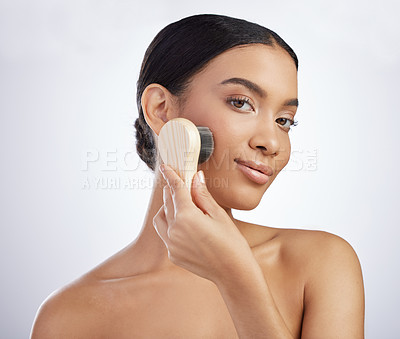 Buy stock photo Studio shot of an attractive young woman exfoliating her face with a brush against a grey background