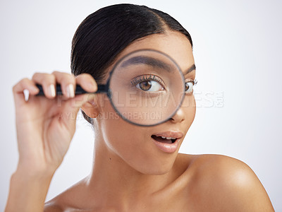 Buy stock photo Studio shot of an attractive young woman looking through a magnifying glass against a grey background