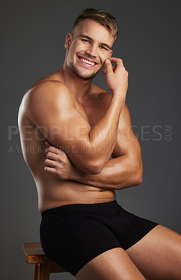 Buy stock photo Cropped portrait of a handsome and athletic young man posing shirtless in studio against a dark background