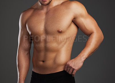 Buy stock photo Cropped shot of an unrecognizable and athletic young man posing shirtless in studio against a dark background