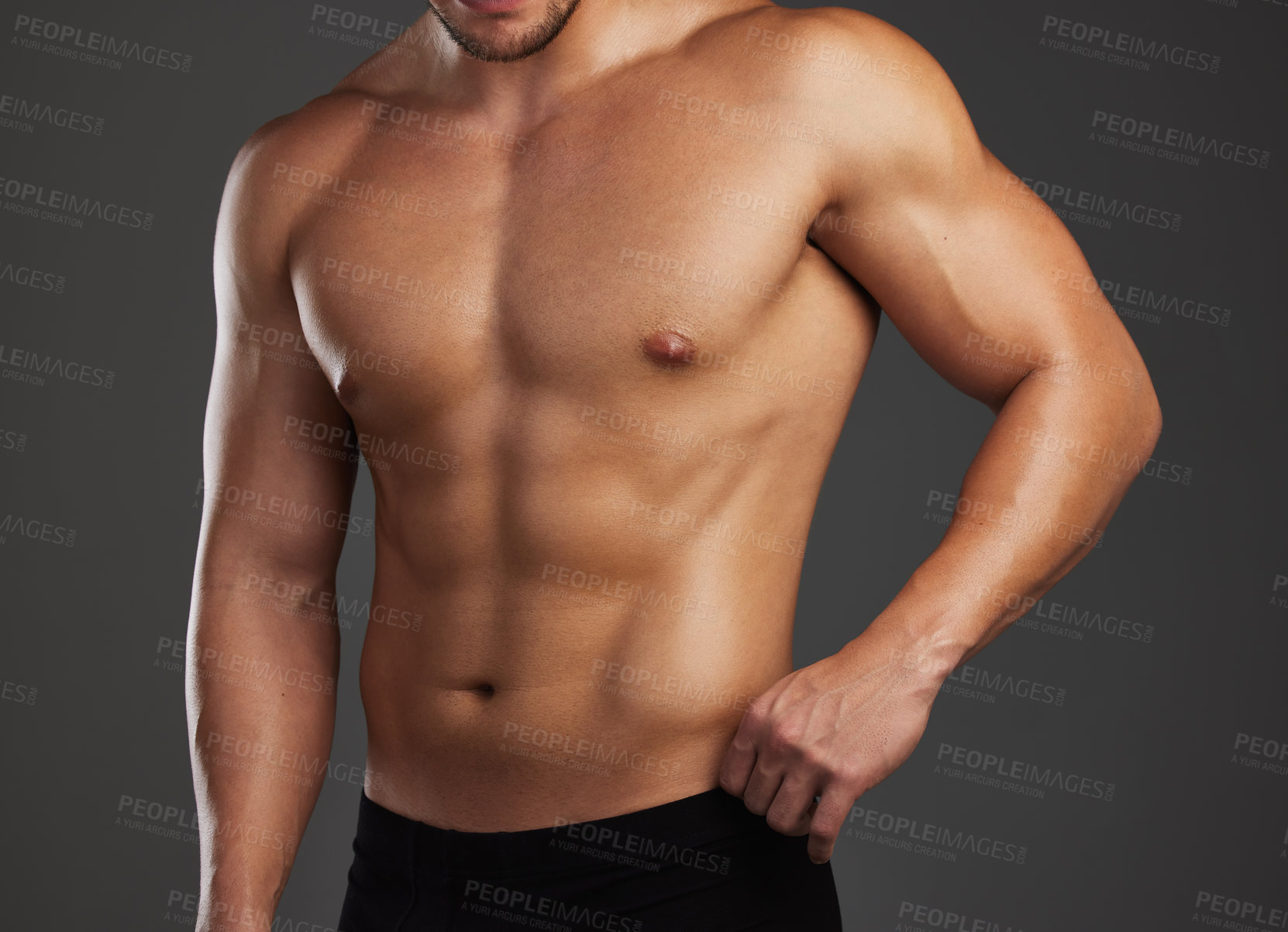 Buy stock photo Cropped shot of an unrecognizable and athletic young man posing shirtless in studio against a dark background