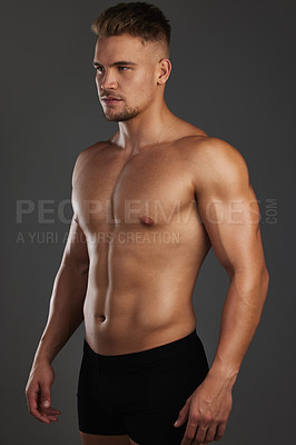 Buy stock photo Cropped shot of a handsome and athletic young man posing shirtless in studio against a dark background