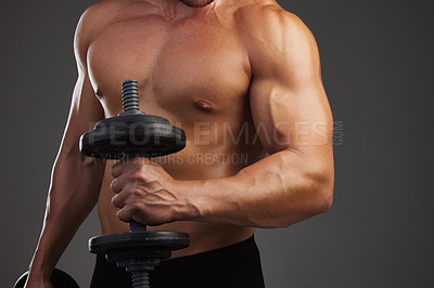 Buy stock photo Cropped shot of an unrecognizable and athletic young man lifting weights while shirtless in studio against a dark background