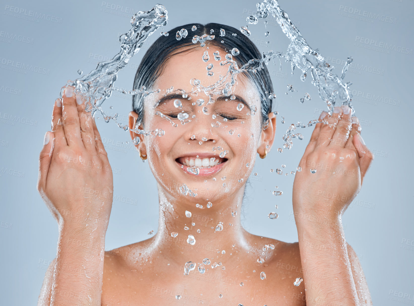 Buy stock photo Shot of a young woman washing her face in the shower against a grey background