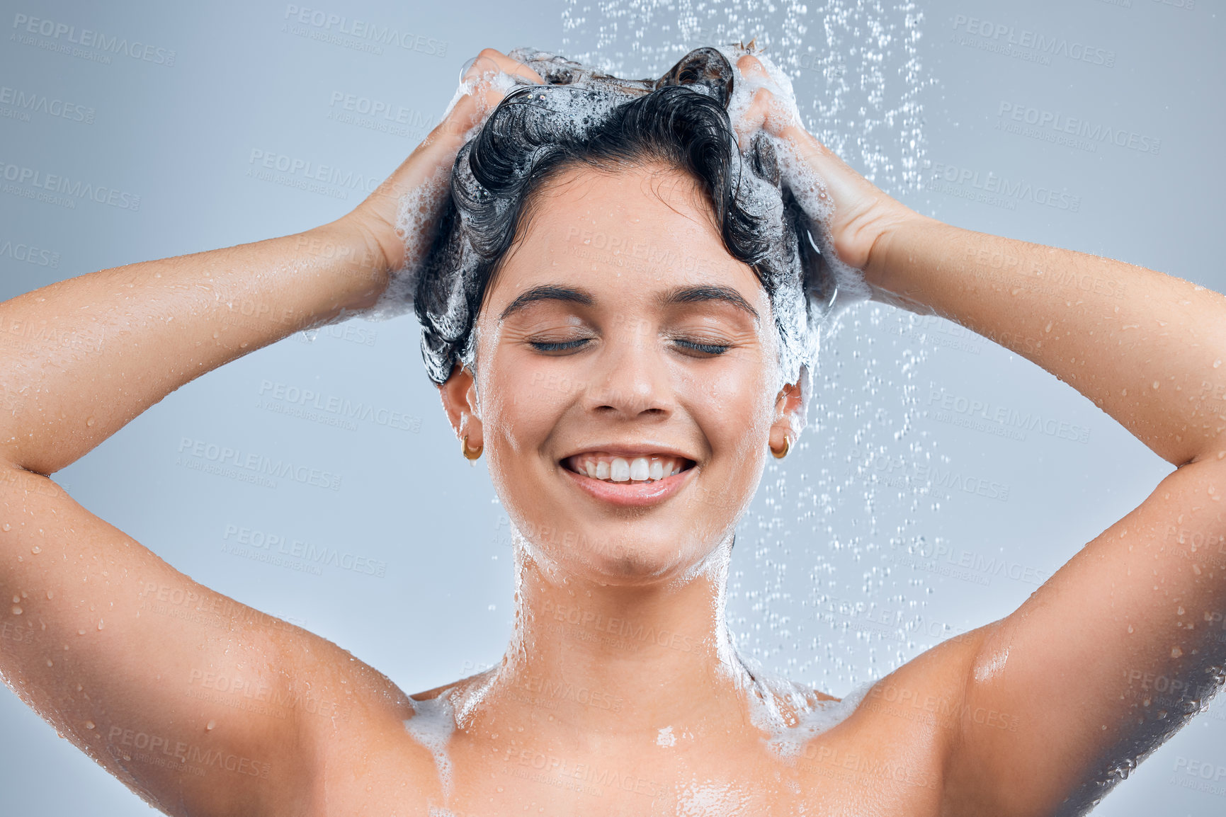 Buy stock photo Shot of a young woman washing her hair in the shower against a grey background