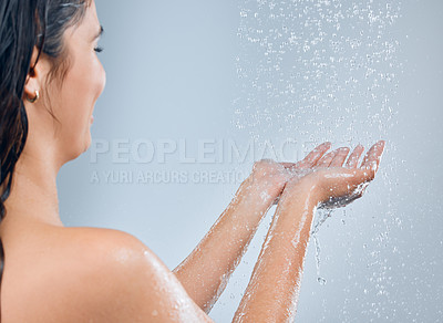 Buy stock photo Shot of a young woman catching water in the shower against a grey background