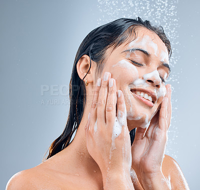 Buy stock photo Woman, smile and face for hygiene shower, wash or clean against a blue studio background. Happy, female skincare splash and model person for body wellness, cosmetics soap or healthy skin treatment