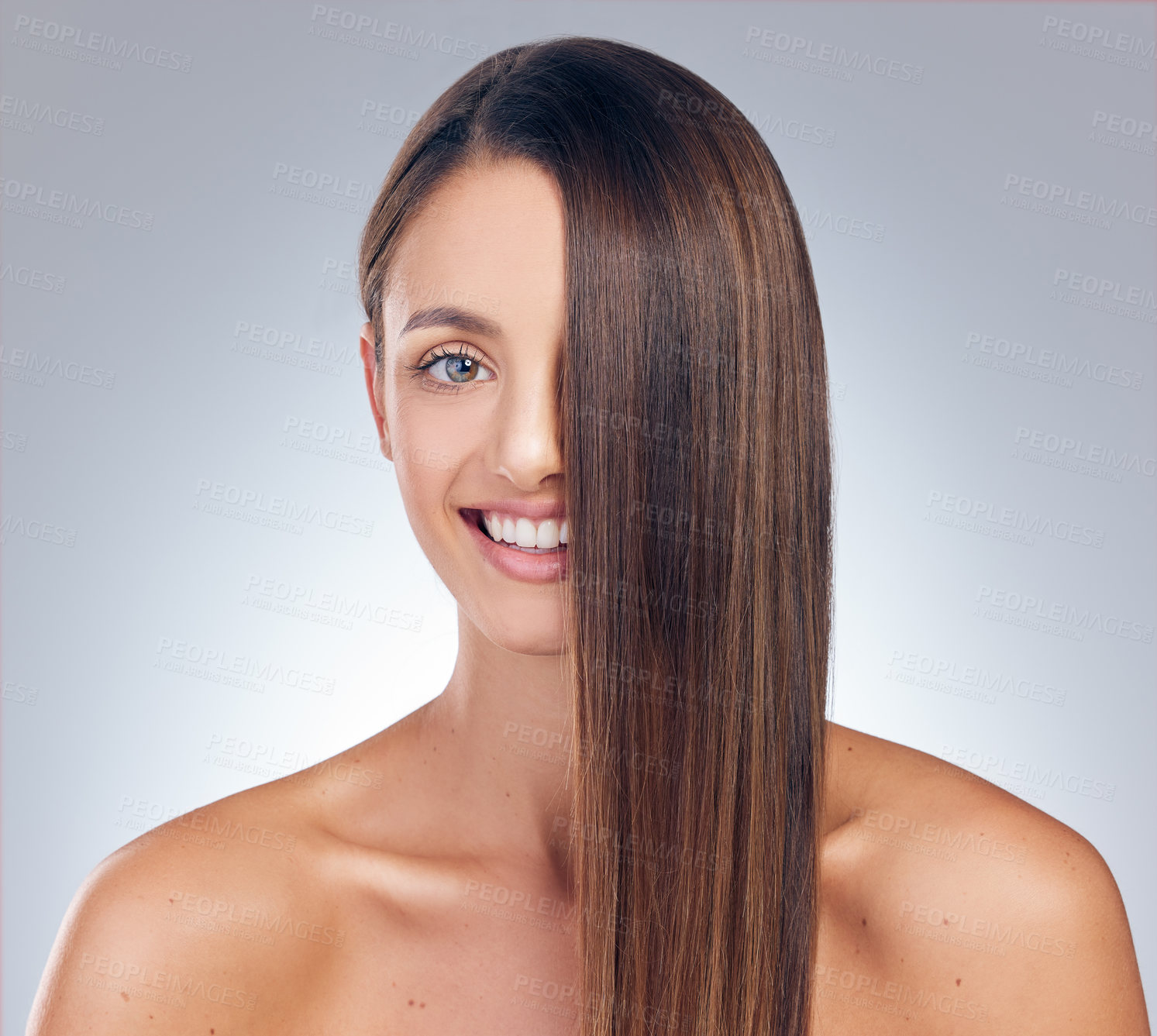 Buy stock photo Shot of an attractive young woman standing alone in the studio and posing with her hair covering half of her face