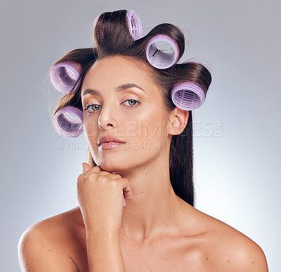 Buy stock photo Shot of an attractive young woman standing alone in the studio and posing with rollers in her hair