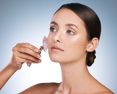 Buy stock photo Face roller, woman and rose quartz for slim face with skincare, results in blue background. Female person, face and pride with cosmetic product for glow, dermatology and anti aging in studio backdrop