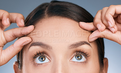 Buy stock photo Close up, woman and hands on forehead in studio for skin care, wellness and thinking of facial. Eyes, filler and idea for dermatology by blue background with cosmetics and collagen for detox 