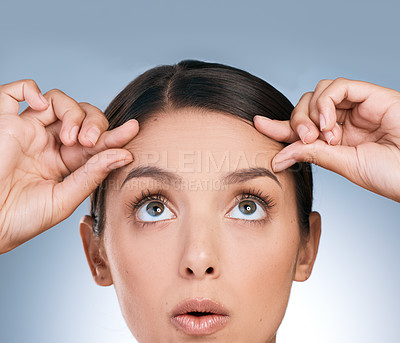 Buy stock photo Shot of a beautiful young woman checking her forehead against a blue background