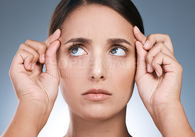 Buy stock photo Shot of a beautiful young woman checking her forehead against a blue background