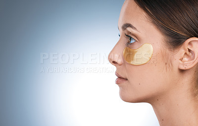 Buy stock photo Side shot of a young attractive woman wearing an under eye patch against a blue background