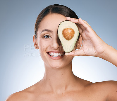 Buy stock photo Portrait of an attractive young woman posing with a sliced avocado against a blue background