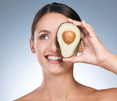 Buy stock photo Shot of an attractive young woman posing with a sliced avocado against a blue background