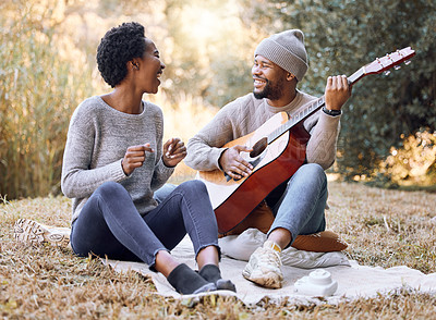 Buy stock photo Shot of a young man serenading his girlfriend while playing the guitar on a camping trip