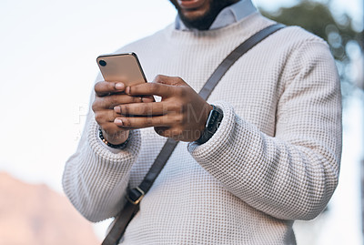 Buy stock photo Cropped shot of an unrecognizable businessman sending a text while standing outside in the city