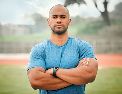 Buy stock photo Cropped portrait of a handsome young male athlete standing outside with his arms folded