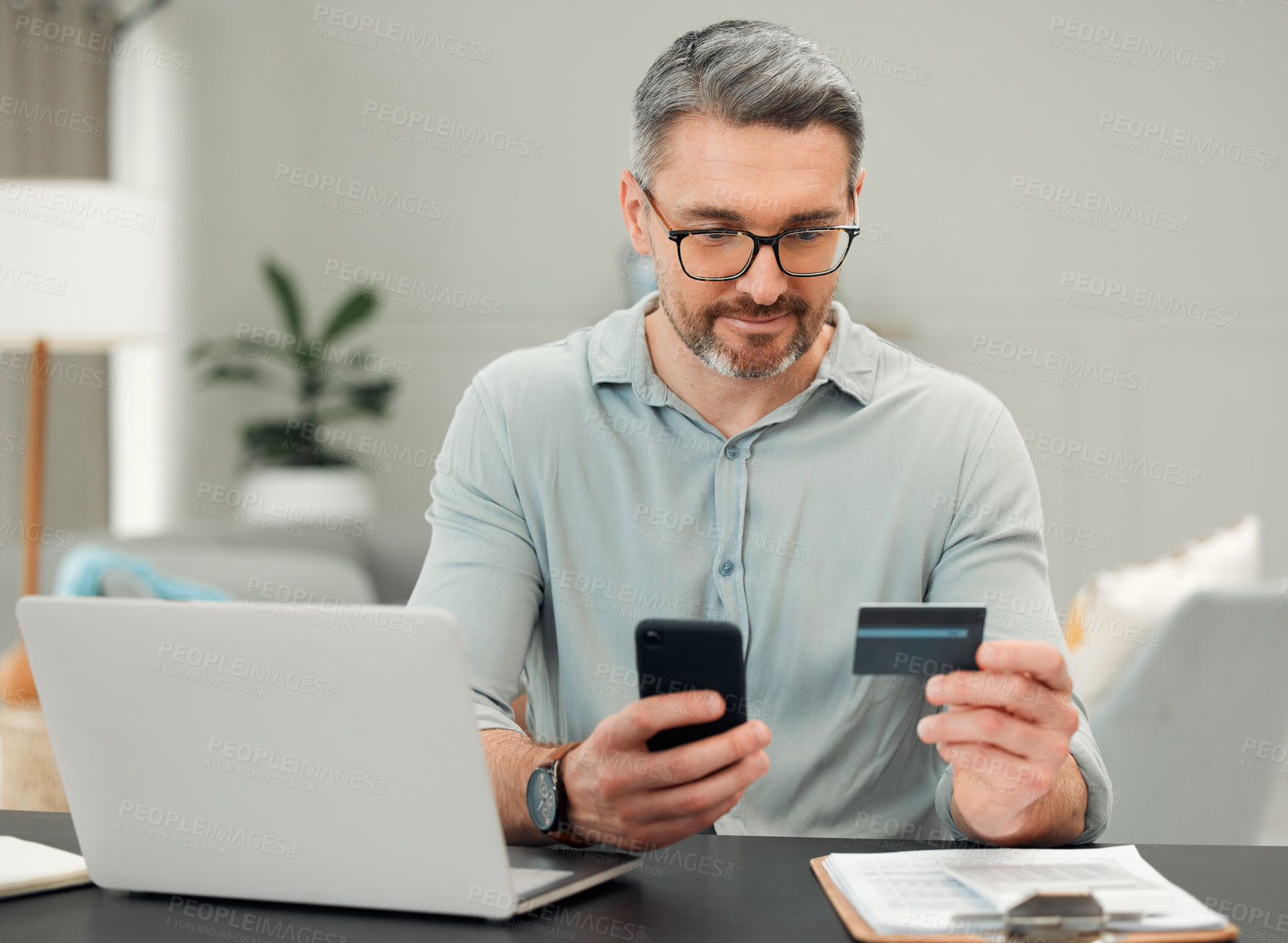 Buy stock photo Cropped shot of a handsome mature man paying bills while sitting at his desk at home