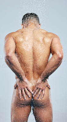 Buy stock photo Studio shot of a handsome young man taking a shower against a grey background