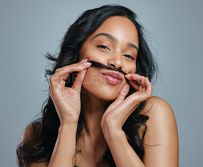 Buy stock photo Studio portrait of an attractive young woman making a moustache with her hair against a grey background