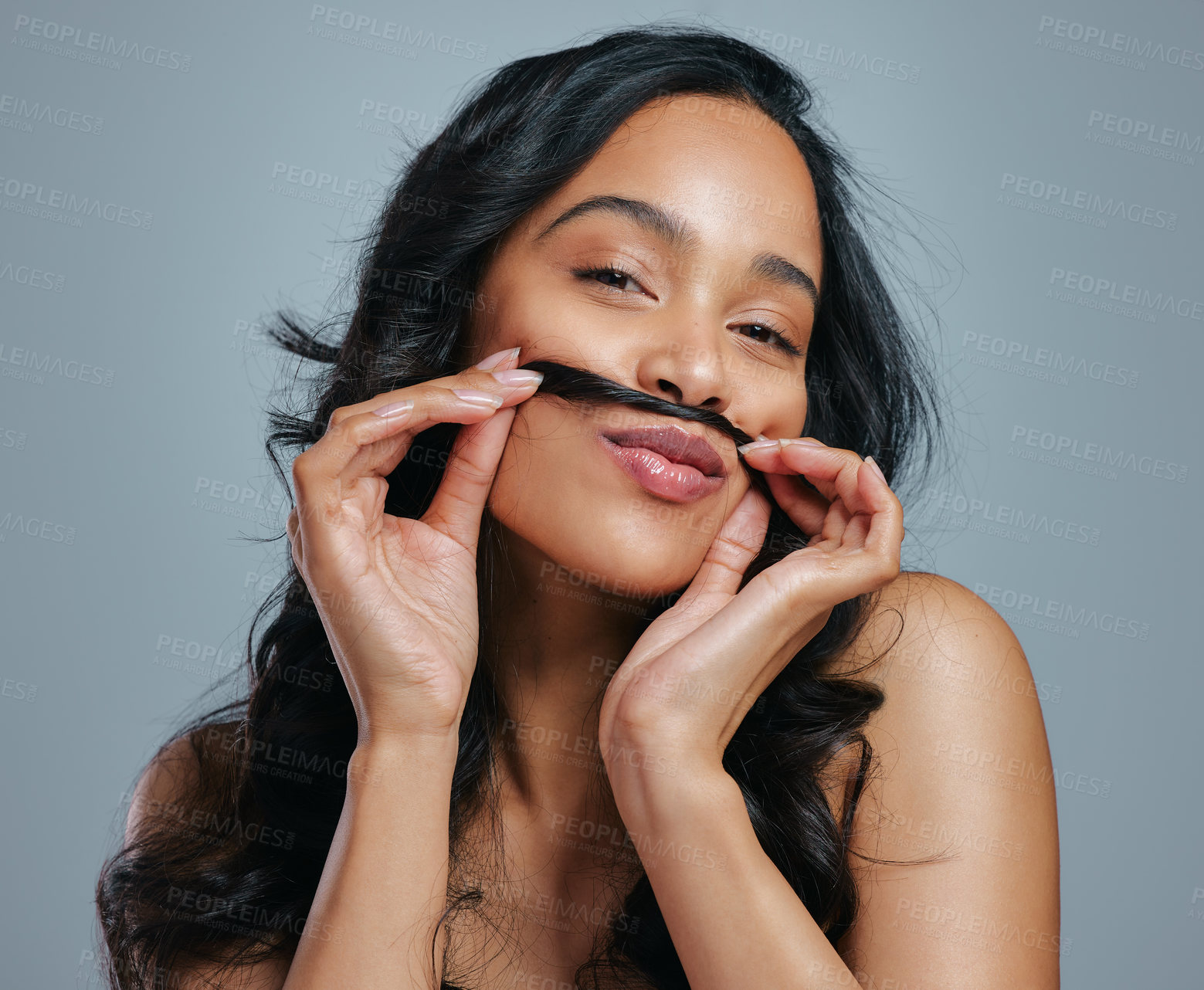 Buy stock photo Studio portrait of an attractive young woman making a moustache with her hair against a grey background