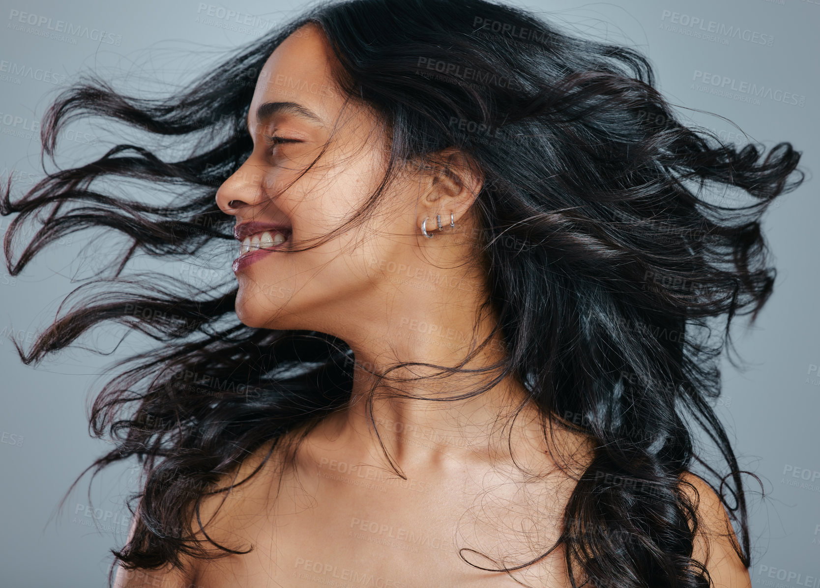 Buy stock photo Studio shot of an attractive young woman tossing her hair against a grey background