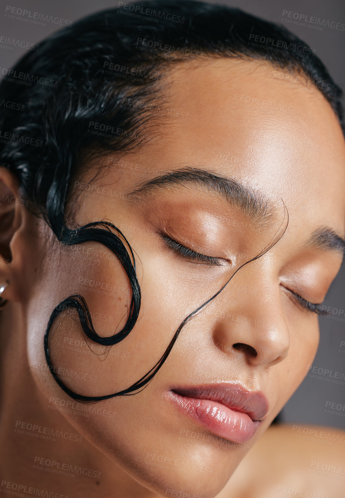 Buy stock photo Studio shot of an attractive young woman posing with a strand of wet hair on her face