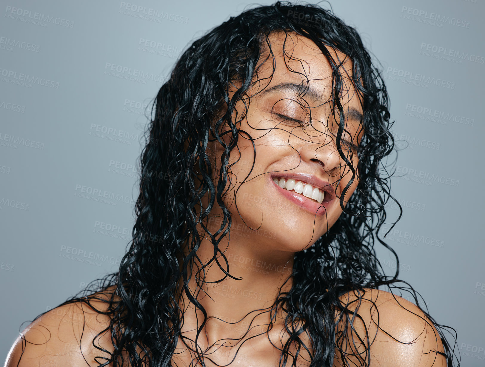 Buy stock photo Studio shot of an attractive young woman posing with wet hair against a grey background