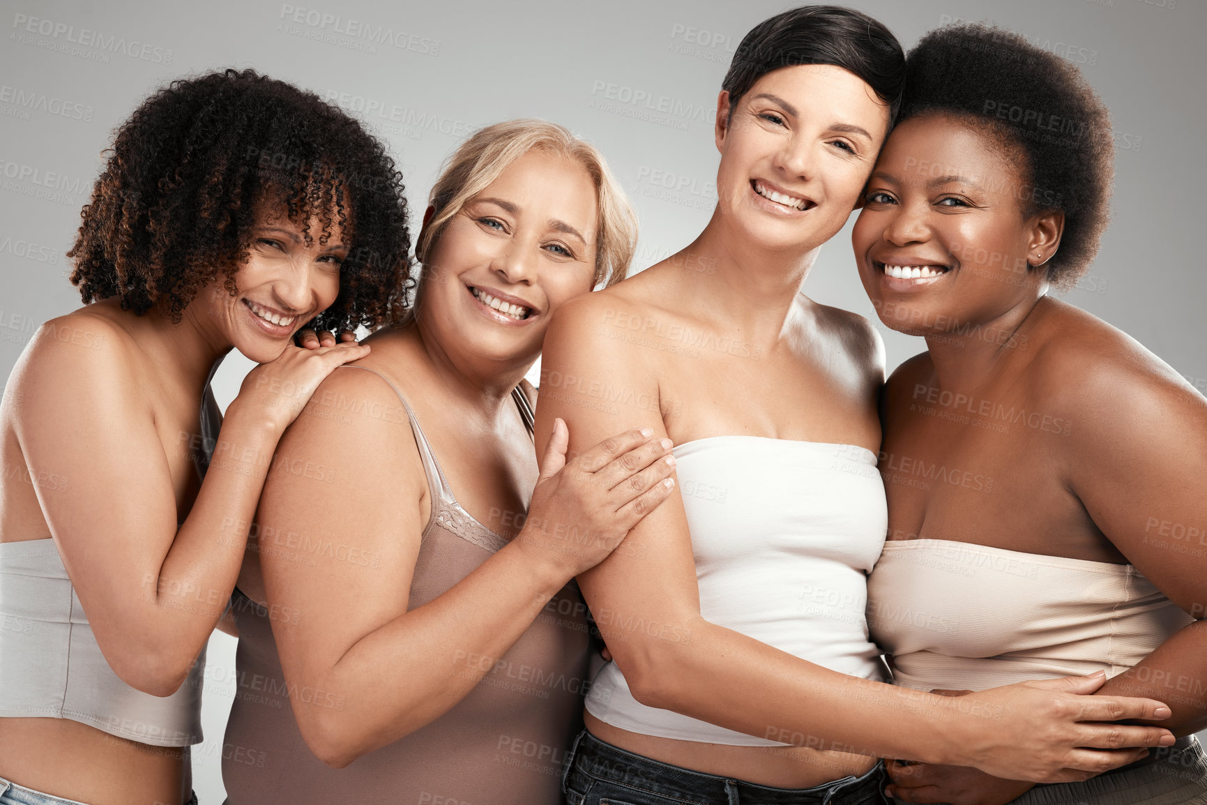 Buy stock photo Shot of a diverse group of women standing and hugging each other in the studio