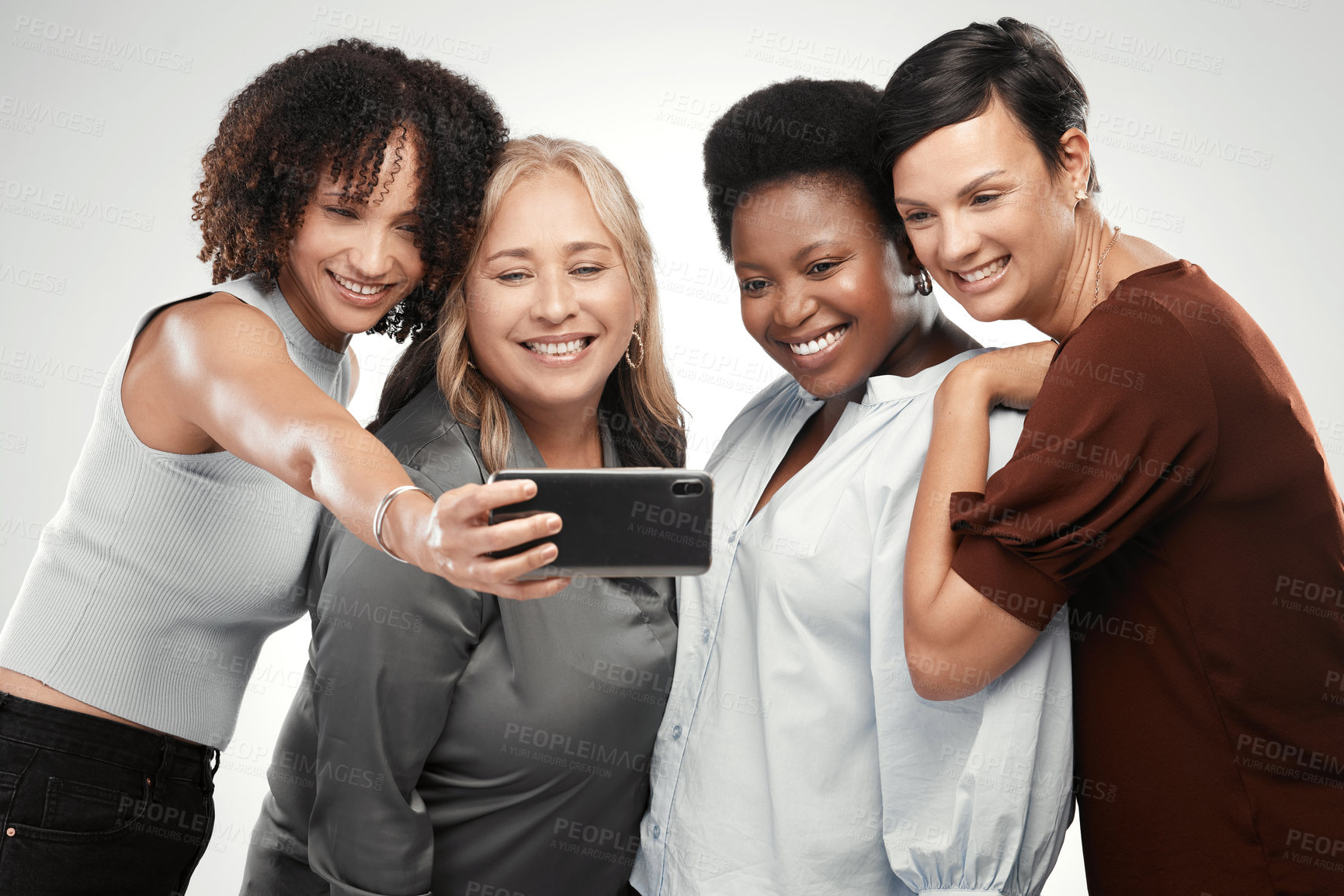 Buy stock photo Shot of a diverse group of women standing close together in the studio and take a selfie with a cellphone