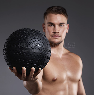 Buy stock photo Shot of a sporty young man holding an exercise ball while standing against a grey background