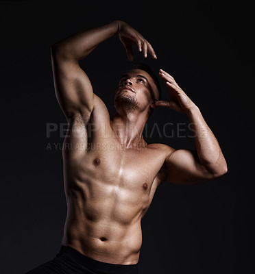 Buy stock photo Shot of a muscular young man posing against a black background
