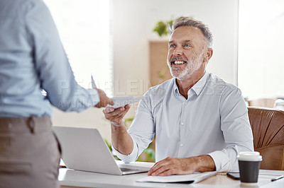 Buy stock photo Shot of a mature businessman receiving a document from his colleague in a modern office