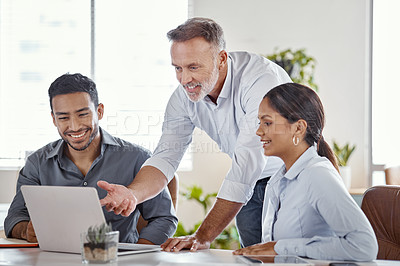 Buy stock photo Shot of a group of businesspeople using a laptop in a modern office