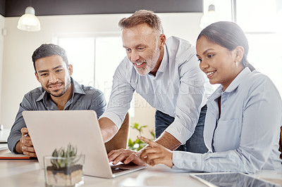 Buy stock photo Shot of a group of businesspeople using a laptop in a modern office