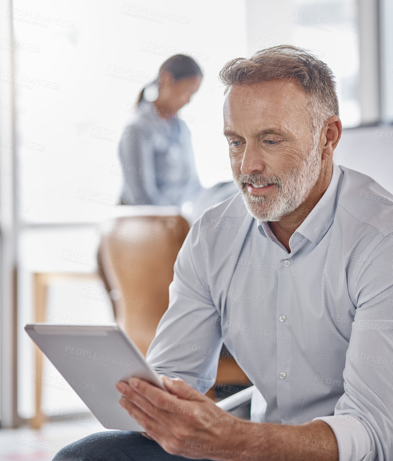 Buy stock photo Shot of a mature businessman using a digital tablet in a modern office