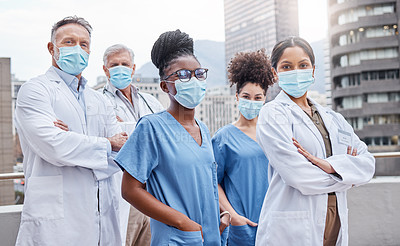 Buy stock photo Shot of a group of doctors standing with their arms crossed in the city
