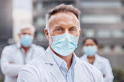 Buy stock photo Shot of a group of doctors wearing masks while in the city