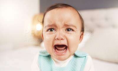 Buy stock photo Shot of an adorable little girl crying while sitting on a bed