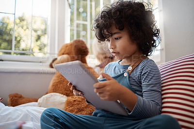 Buy stock photo Shot of an adorable young boy using a digital tablet in his bedroom at home