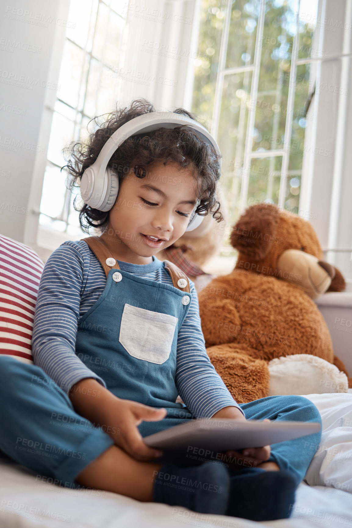 Buy stock photo Shot of an adorable young boy using a digital tablet and headphones in his bedroom at home