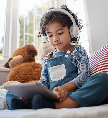 Buy stock photo Shot of an adorable young boy using a digital tablet and headphones in his bedroom at home