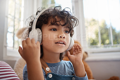 Buy stock photo Shot of an adorable young boy using headphones in his bedroom at home