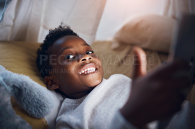 Buy stock photo Shot of a little boy using his digital tablet while lying on the floor