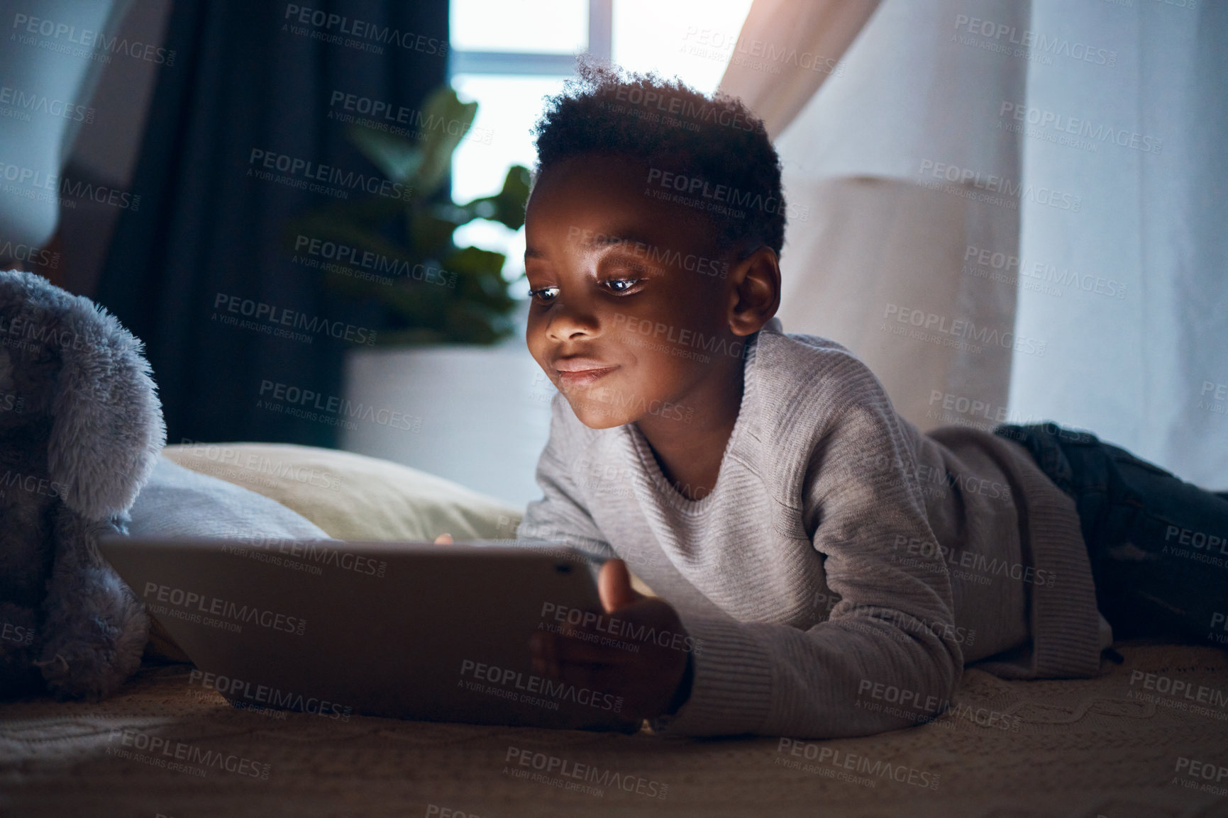 Buy stock photo Shot of a little boy using his digital tablet while lying on the floor