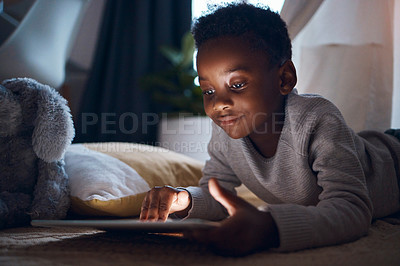 Buy stock photo Shot of a little boy using his digital tablet while lying on the floor